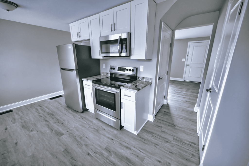 an empty kitchen with white cabinets and stainless steel appliances