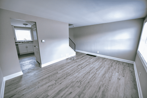 an empty living room with white walls and wood flooring