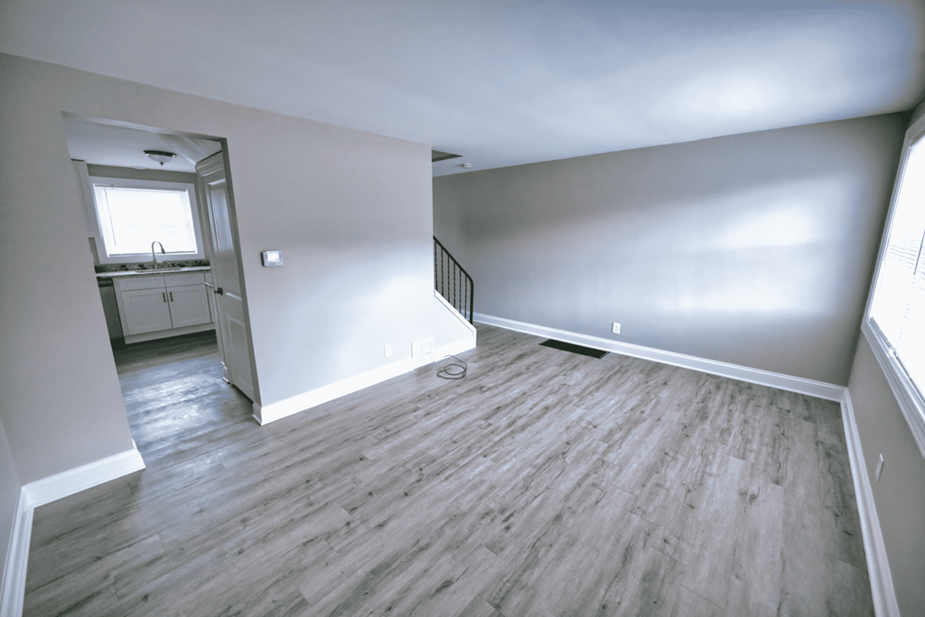 an empty living room with white walls and wood flooring