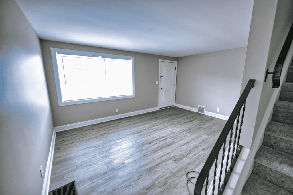an empty living room with wood floors and a large window