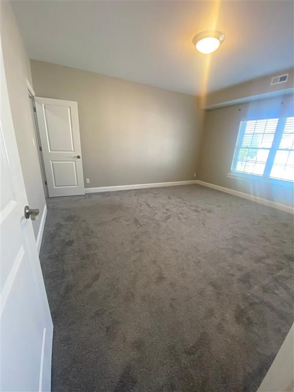 an empty living room with a carpeted floor and a window
