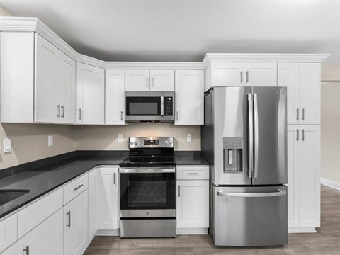 a white kitchen with stainless steel appliances and white cabinets