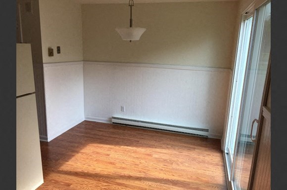 a empty living room with wood floors and a white wall