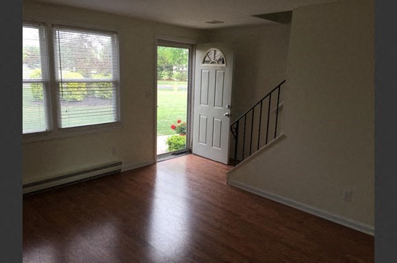an empty living room with a door and a staircase