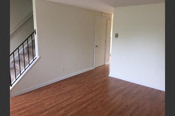 an empty living room with a hard wood floor and a door