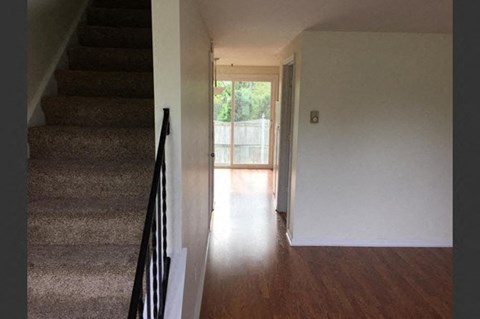 a hallway with stairs and a door to a living room