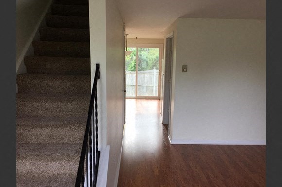 a hallway with stairs and a door to a living room