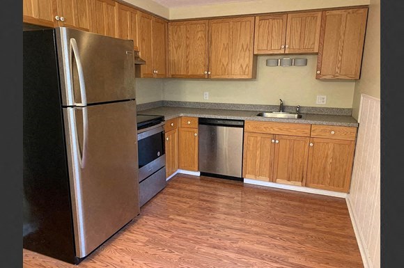 a kitchen with wooden cabinets and a stainless steel refrigerator