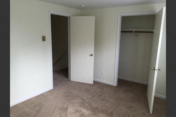 an empty bedroom with a closet and a staircase