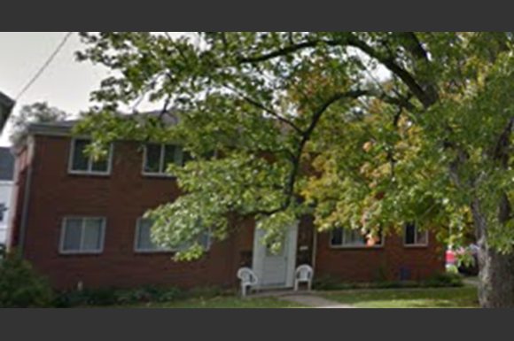 a red brick house with a tree in front of it