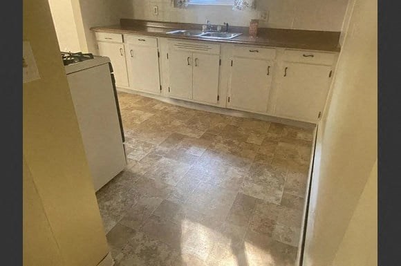 an empty kitchen with white cabinets and a sink