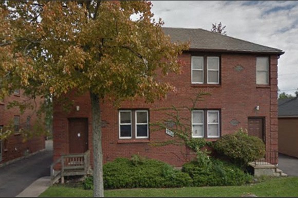 a red brick house with a tree in front of it