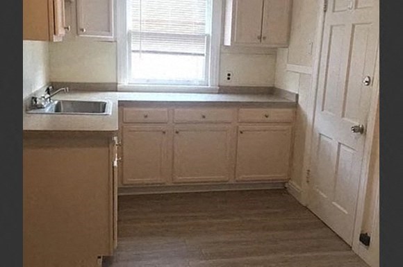 a kitchen with white cabinets and a sink and a window