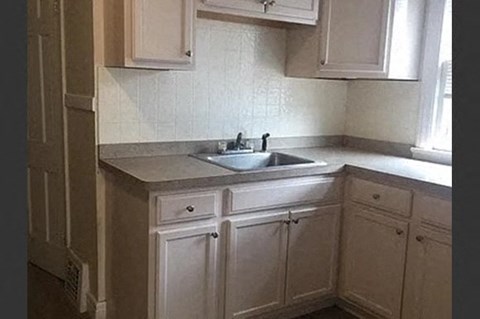 a small kitchen with a sink and white cabinets