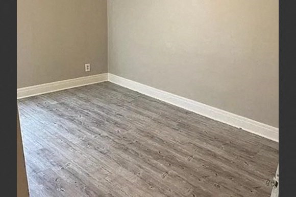 a empty room with wooden flooring and a white wall