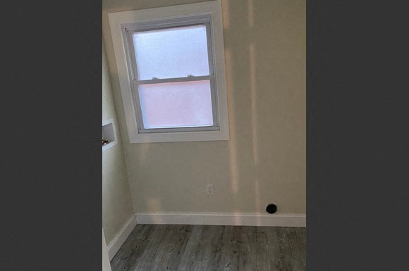 an empty room with a window and wooden floors