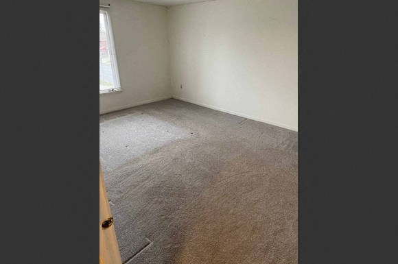 an empty room with a carpeted floor and a window
