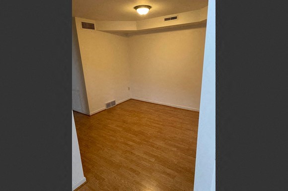 an empty room with a wood floor and white walls