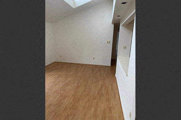 an empty room with a wood floor and white walls
