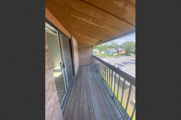 a balcony with a wooden floor and a brick building