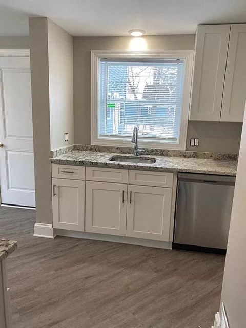 a kitchen with white cabinets and a sink and a window