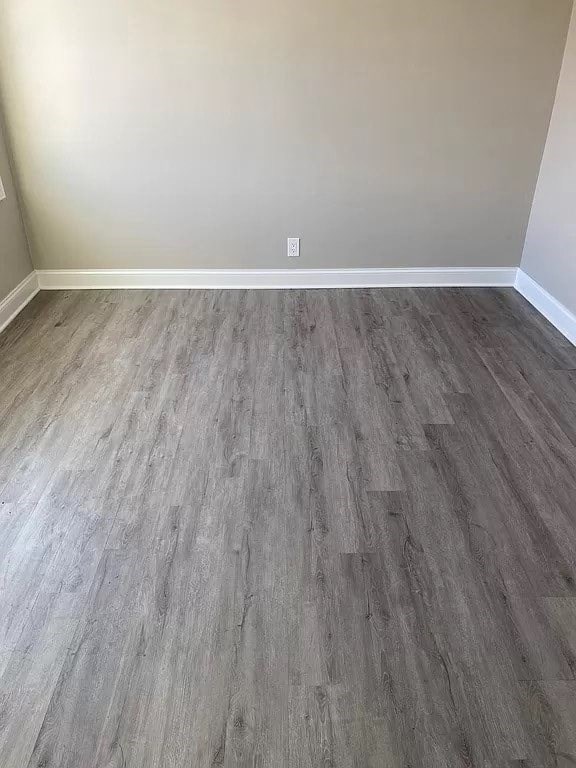 a empty room with a wooden floor and a white wall