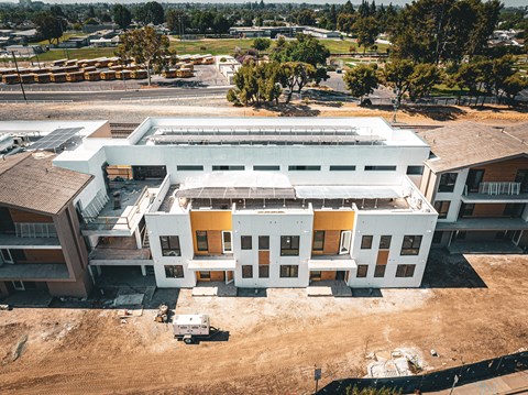 A large white building with a yellow section in the middle is under construction.