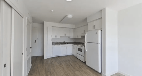 A white kitchen with a refrigerator, sink, and cabinets.