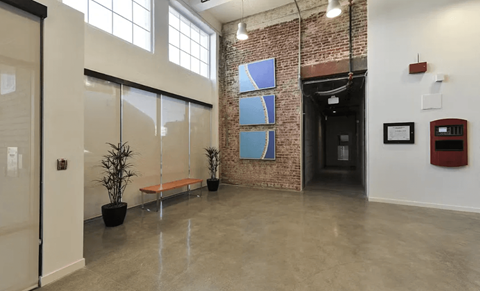 A hallway with a bench, a plant, and a brick wall.