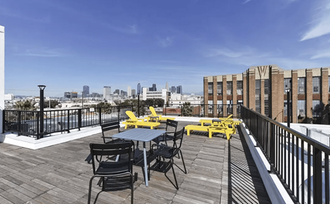 A balcony with a table and chairs overlooking a city skyline.