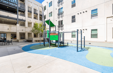 A playground with a slide and swings in a courtyard.