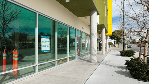 the front of a building with glass windows and a sidewalk