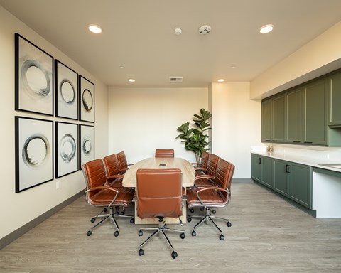 A conference room with a table surrounded by chairs and pictures on the wall.
