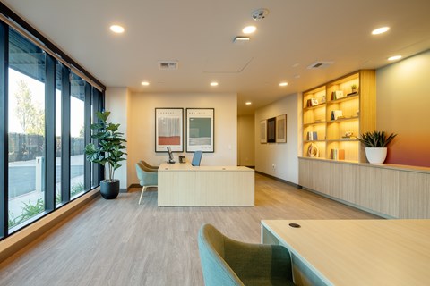 A modern office space with a reception desk, chairs, and a large window.