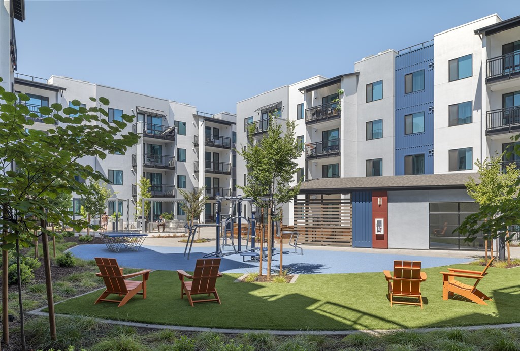 A modern apartment complex with a playground and seating area.