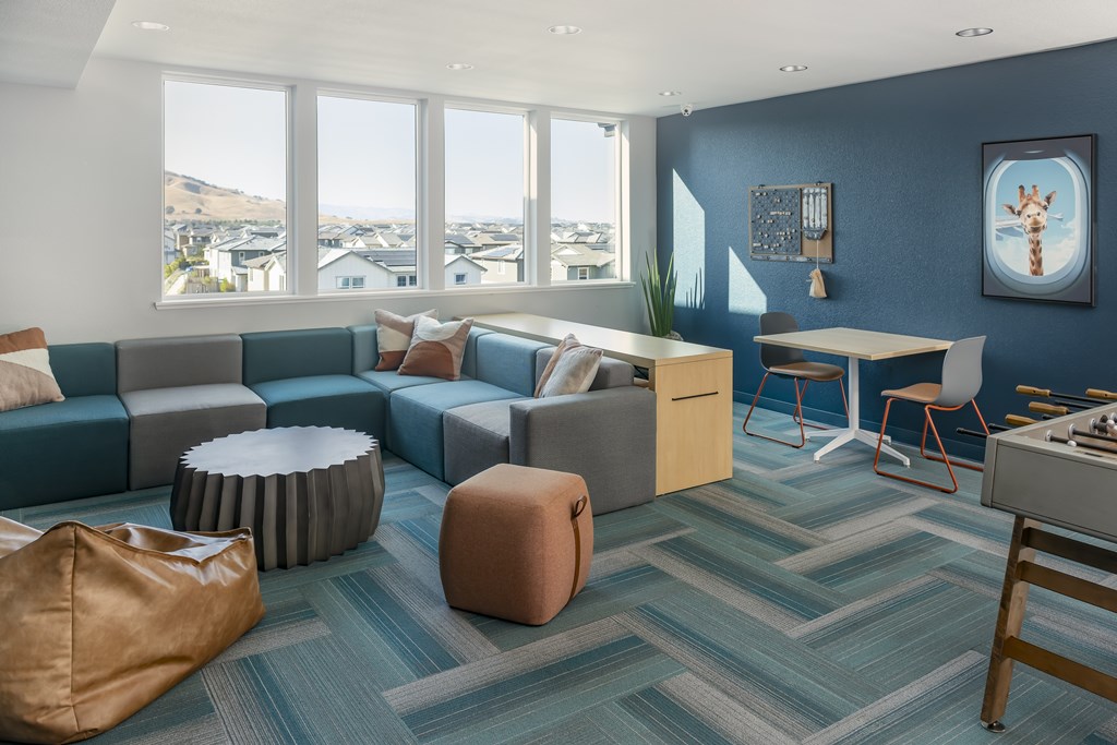 A living room with a blue couch and a brown ottoman.