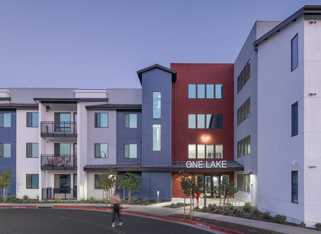 A person is walking in front of a building called One Lake.