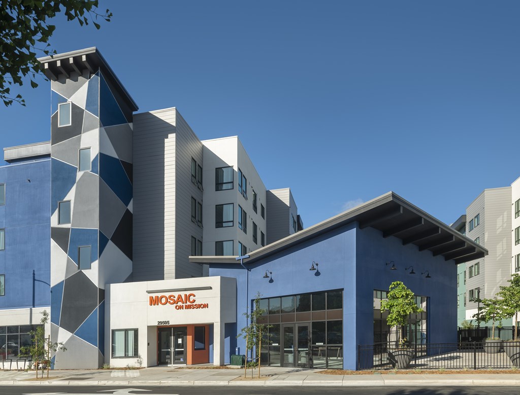 A modern building with a blue and white facade and the words "MOSAIC" on the front.