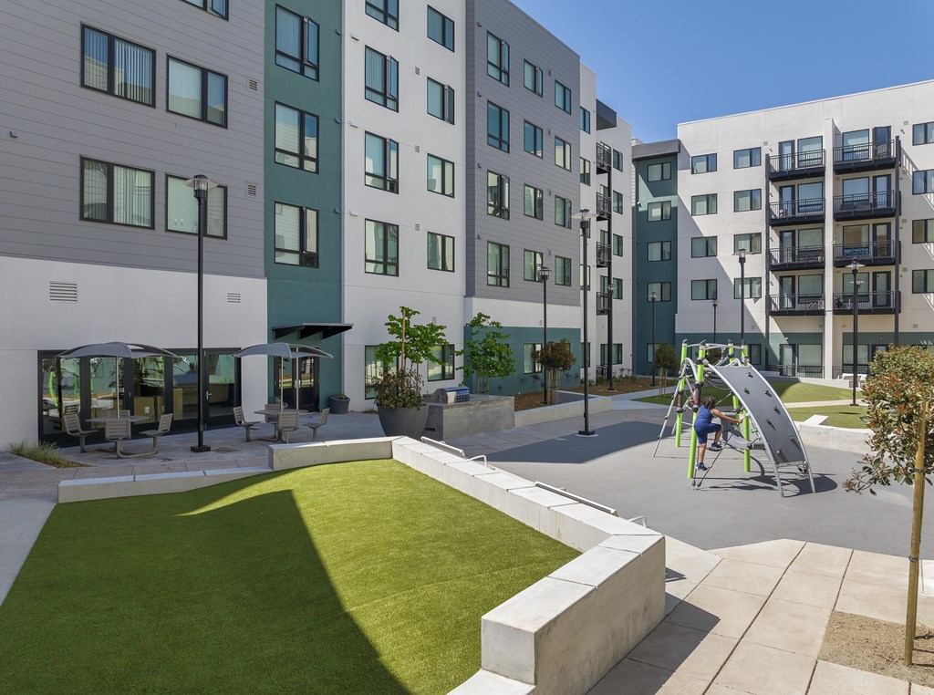 A playground with a slide and a child sitting on it.