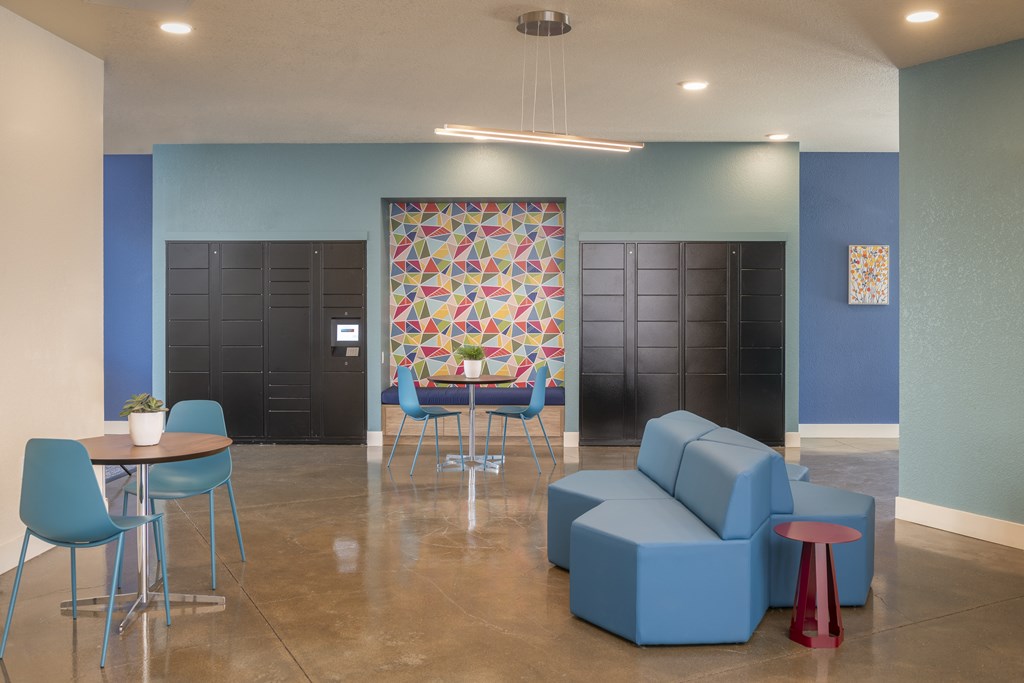A room with blue chairs and a table with a plant on it.