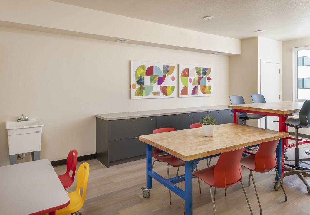 A room with a table and chairs and a painting on the wall.