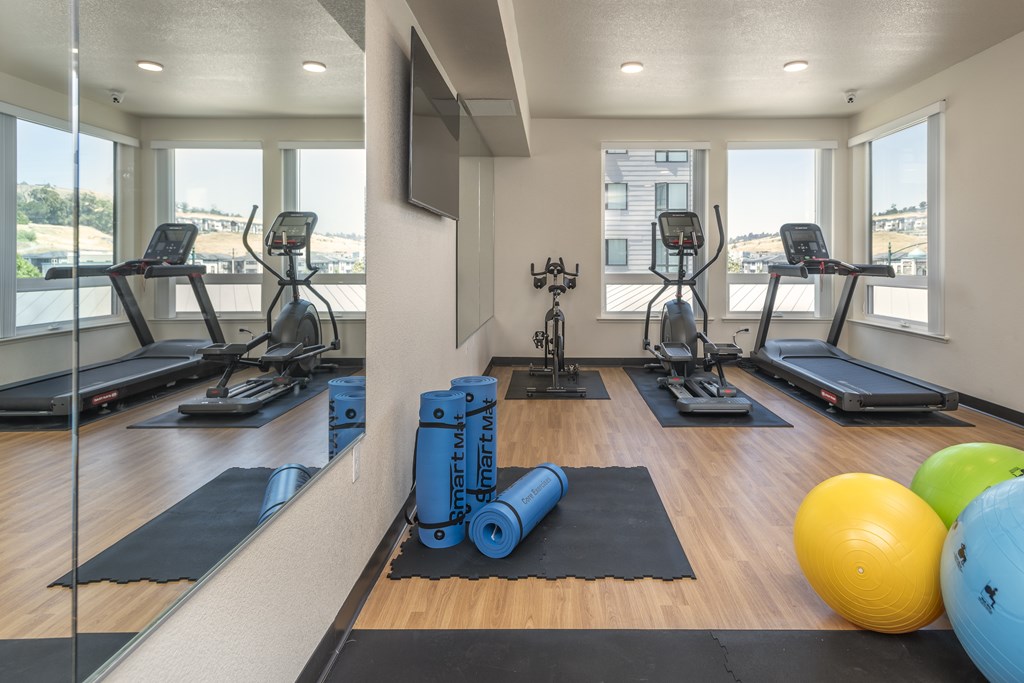 A gym with treadmills, exercise balls, and weights.