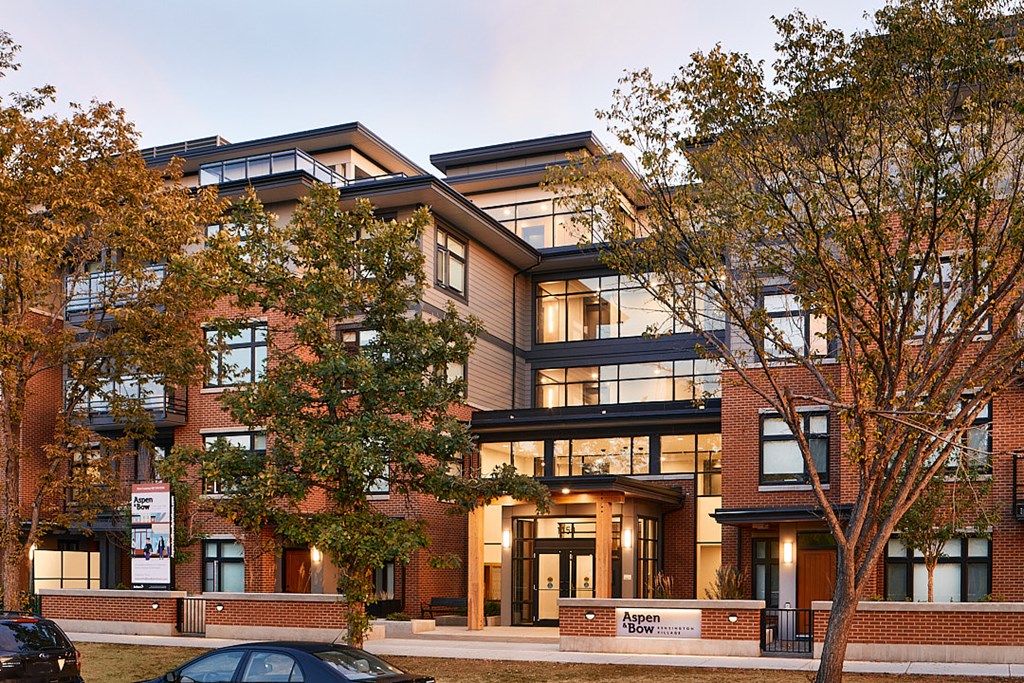 A modern apartment building with a car parked in front.