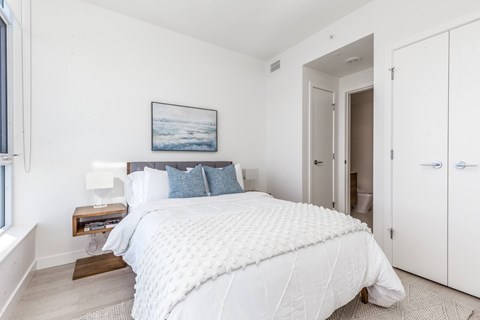 A bedroom with a large bed and a picture on the wall.