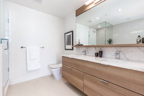 A bathroom with a toilet, sink, and mirror.