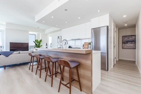 A modern kitchen with a bar area and wooden flooring.