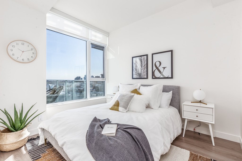 A bedroom with a large bed, a nightstand, and a clock on the wall.