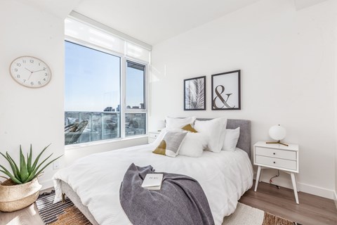 A bedroom with a large bed, a nightstand, and a clock on the wall.