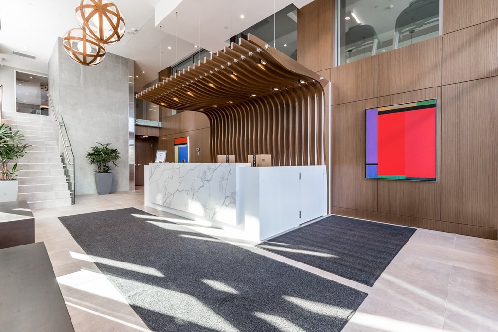 A modern office lobby with a staircase and a large abstract painting on the wall.