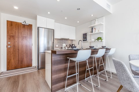 A modern kitchen with white cabinets and a wooden door.